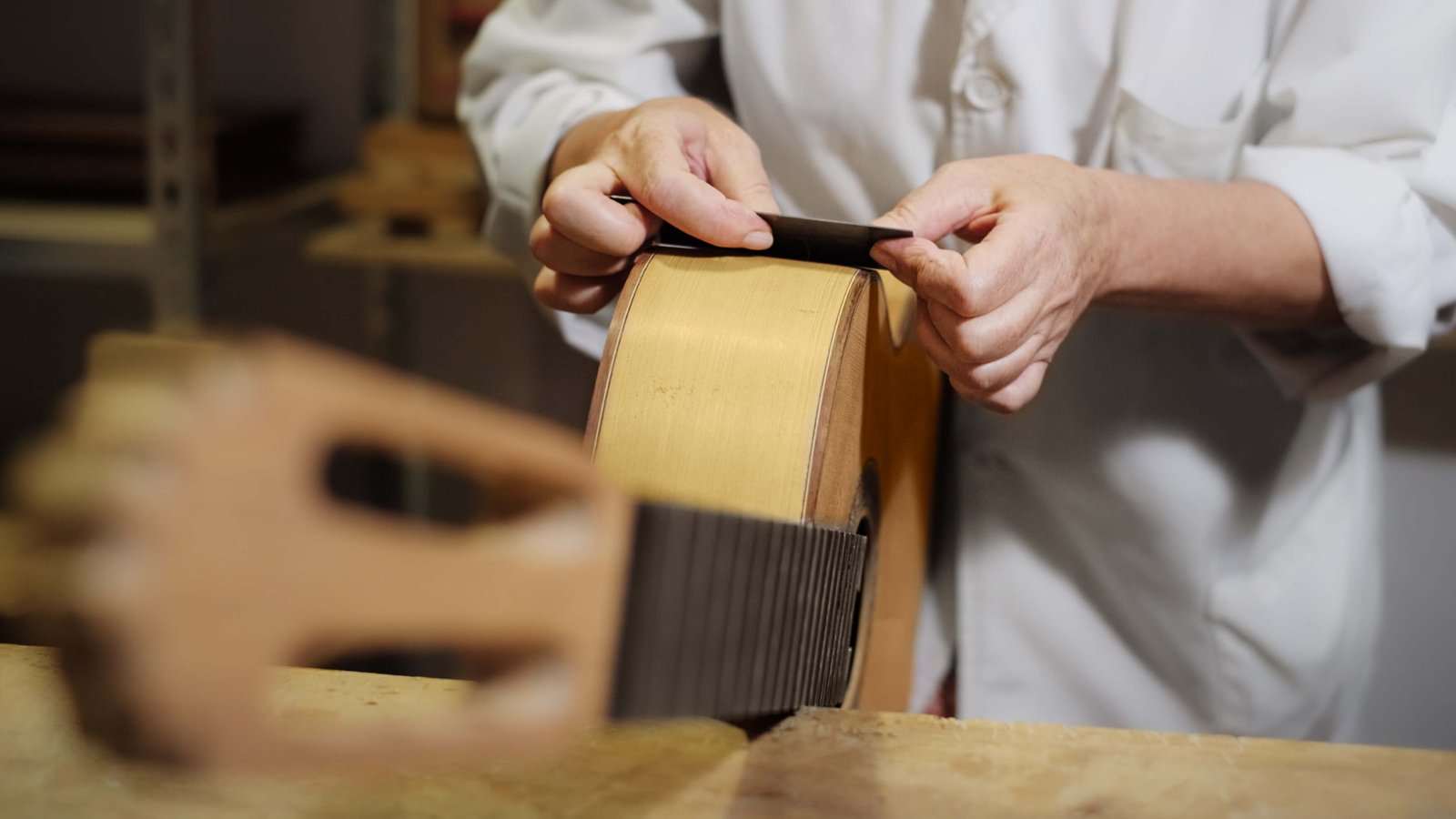 Artisan luthier travaillant sur le manche d'une guitare en bois